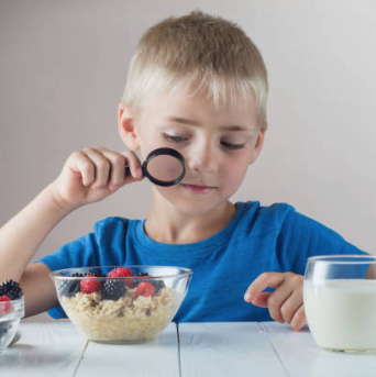 Boy looking at cereal with a magnifying glass