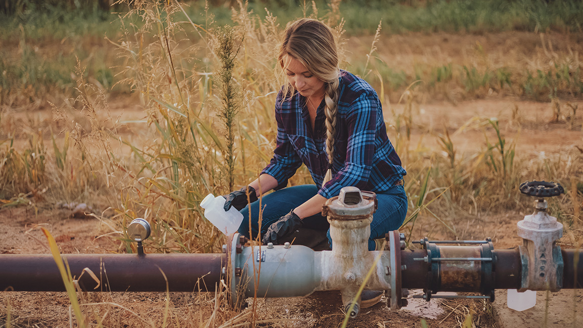 Tara Vander Dussen taking a water sample from the irrigation well.