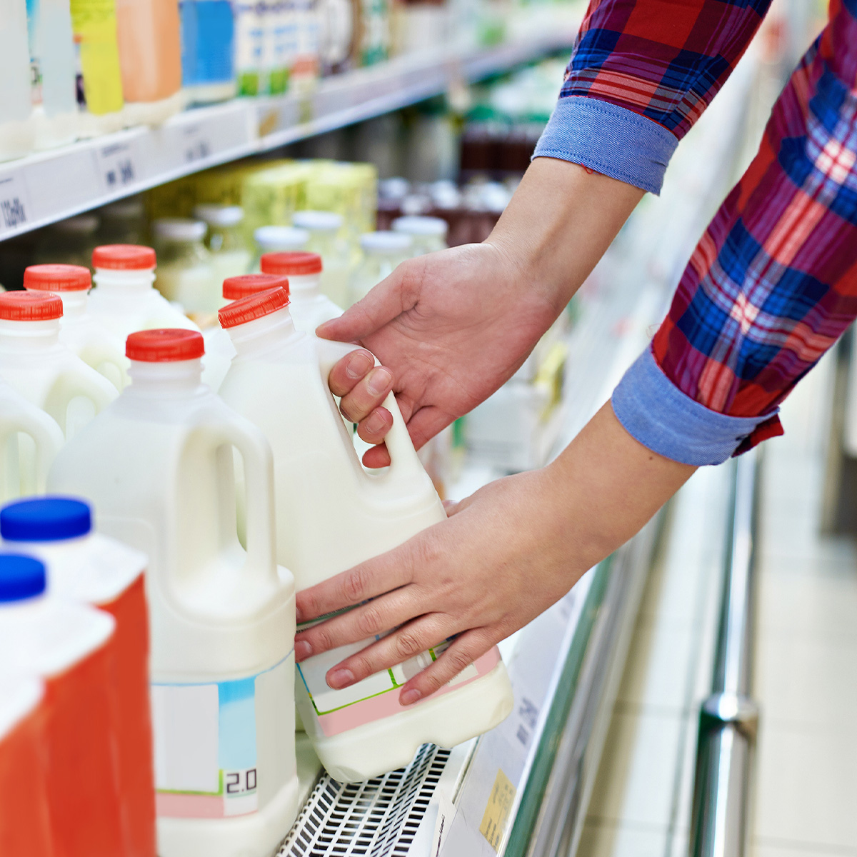 Person grabbing milk from the dairy fridge